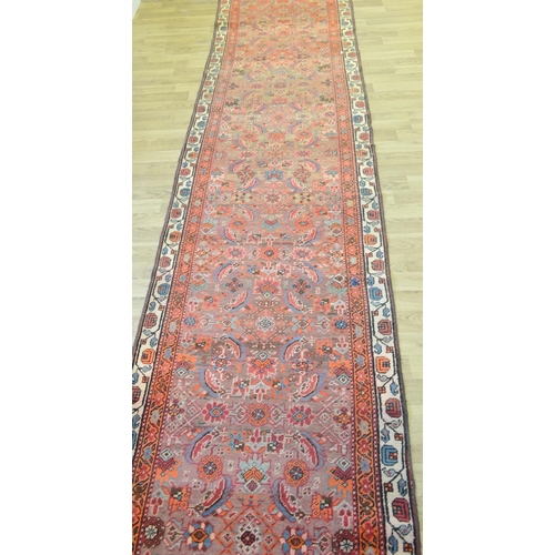 3121 - A Middle Eastern rectangular woollen carpet, the runner with a field of stylised flowers within guar... 