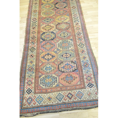 3122 - A Middle Eastern rectangular woollen carpet, the runner with a field of twenty-four geometric guls, ... 