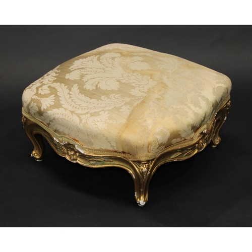 1363 - A 19th century giltwood serpentine footstool, stuffed over top above a shaped frieze carved with flo... 