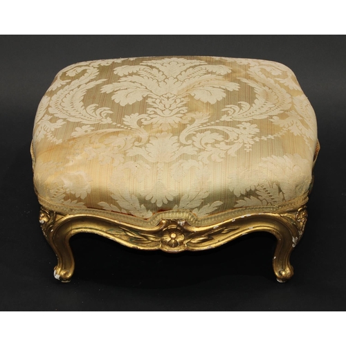 1363 - A 19th century giltwood serpentine footstool, stuffed over top above a shaped frieze carved with flo... 