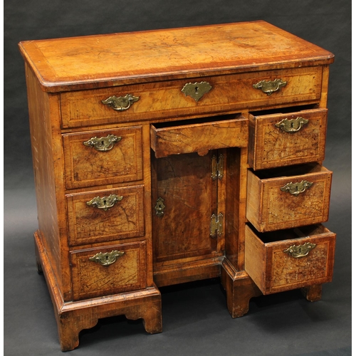 1476 - A George I walnut kneehole desk, rounded rectangular quarter-veneered crossbanded top above a long f... 