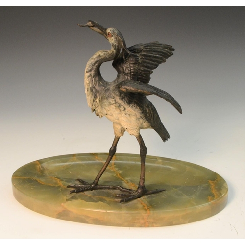 1597 - A late 19th century cold painted stork, a fish in its beak, onyx oval base, 23cm high