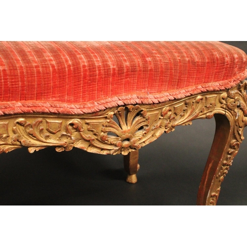 1713 - A Rococo giltwood serpentine stool, stuffed over seat, the deep frieze and cabriole legs pierced and... 