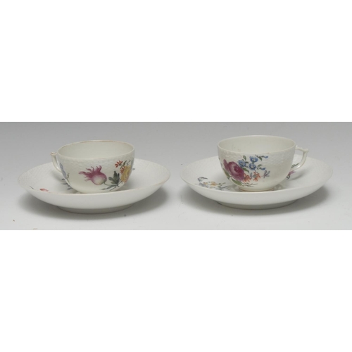 264 - Two  18th century Berlin teacups and saucers, painted with colourful flowers below an ozier moulded ... 