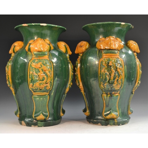 319 - A pair of Chinese lobed ovoid floor vases, moulded with panels of ferocious dragons, glazed in tones... 