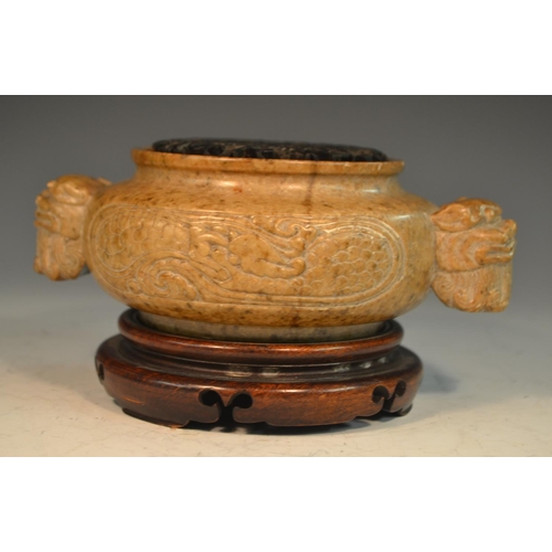 341 - A Chinese brown soapstone ding censer, the sides carved in relief with a ferocious dragon, the proje... 