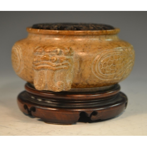 341 - A Chinese brown soapstone ding censer, the sides carved in relief with a ferocious dragon, the proje... 