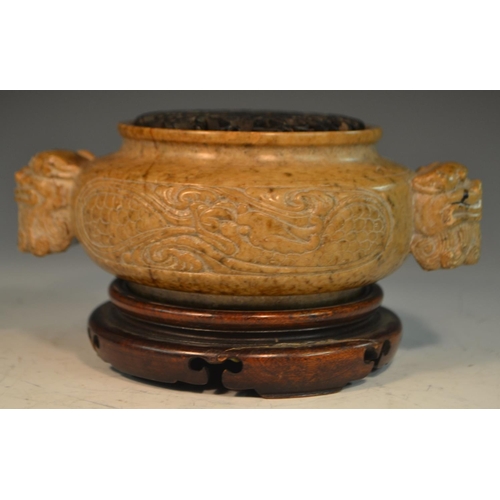 341 - A Chinese brown soapstone ding censer, the sides carved in relief with a ferocious dragon, the proje... 