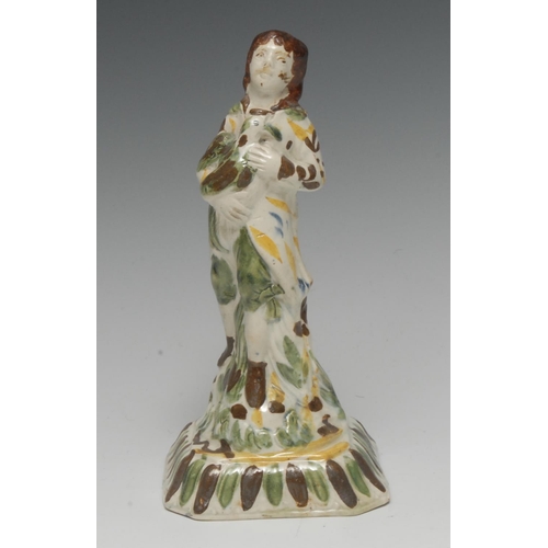 39 - An 18th century Staffordshire creamware figure, of a boy standing holding a bird, flecked in green, ... 