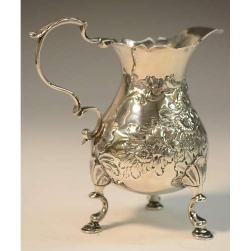 699 - A George III silver pot-bellied cream jug, chased with flowers and stiff leaves, centred by a C-scro... 