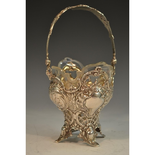 729 - A German silver ogee shaped  sweetmeat basket, pierced and embossed with scrolls and foliage, swing ... 