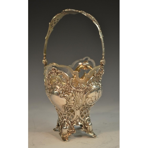 729 - A German silver ogee shaped  sweetmeat basket, pierced and embossed with scrolls and foliage, swing ... 