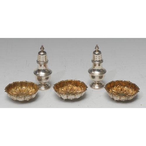 790 - A set of three Victorian silver gilt open salts, embossed with flowerhead, ball feet, C-scroll rims,... 