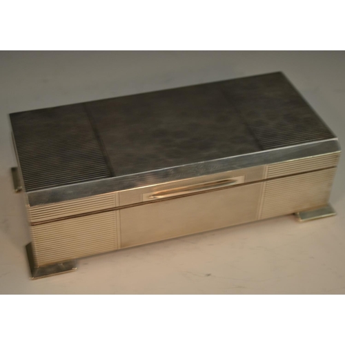 844 - An Art Deco style silver rectangular cigarette box, engine turned and reeded in panels, bracket feet... 