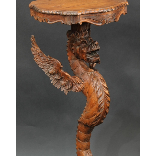 2063 - A Venetian limewood tripod torchere, boldly carved as a dragon monopodia, shaped serpentine plateau,... 