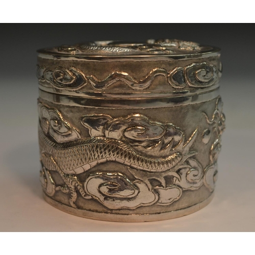 665 - A Chinese silver cylindrical box and cover, chased with ferocious dragons chasing the flaming pearl ... 