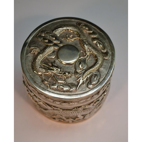 665 - A Chinese silver cylindrical box and cover, chased with ferocious dragons chasing the flaming pearl ... 