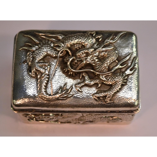 730 - A Japanese silver rounded rectangular box, applied with ferocious dragons on a planished ground, hin... 