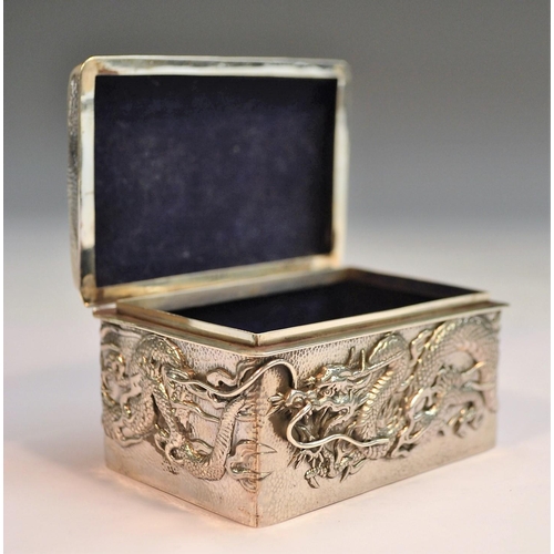 730 - A Japanese silver rounded rectangular box, applied with ferocious dragons on a planished ground, hin... 