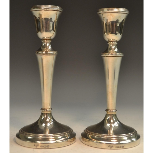 754 - A pair of Elizabeth II silver candlesticks, bell shaped sconces, tapered pillars, domed circular bas... 