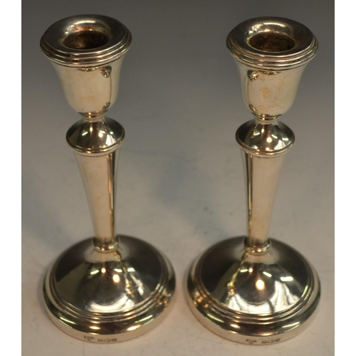 754 - A pair of Elizabeth II silver candlesticks, bell shaped sconces, tapered pillars, domed circular bas... 