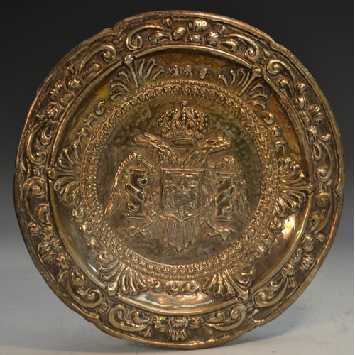 773 - A Portuguese silver coloured metal circular dish, centred by double-headed eagle and armorial, the b... 