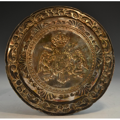 773 - A Portuguese silver coloured metal circular dish, centred by double-headed eagle and armorial, the b... 