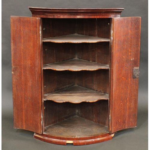 1509 - A George III mahogany crossbanded oak bow fronted wall hanging corner cupboard, moulded cornice abov... 