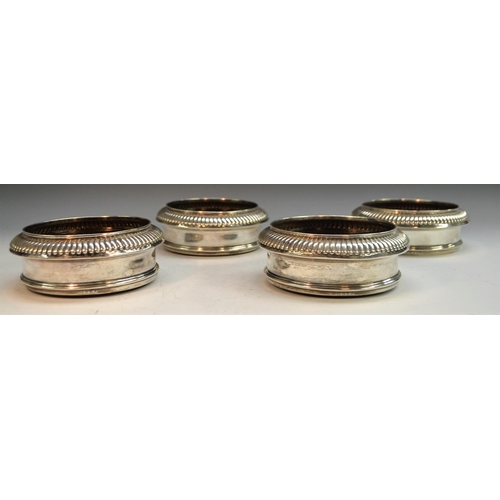 788 - A set of four George III silver circular wine coasters, gadrooned borders, draught turned bases, 15c... 