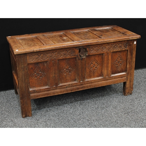 1289 - A 17th century oak blanket chest,  above a four panel front carved with lozenges, stile feet, 117cm ... 