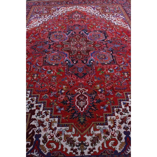 1593 - A large rectangular woollen carpet, colourfully worked in the typical Middle Eastern manner with hoo... 