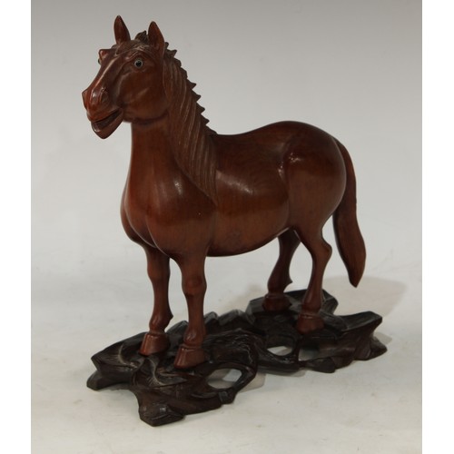 64 - A Japanese hardwood carving, of a horse, standing four square, carved and pierced stand