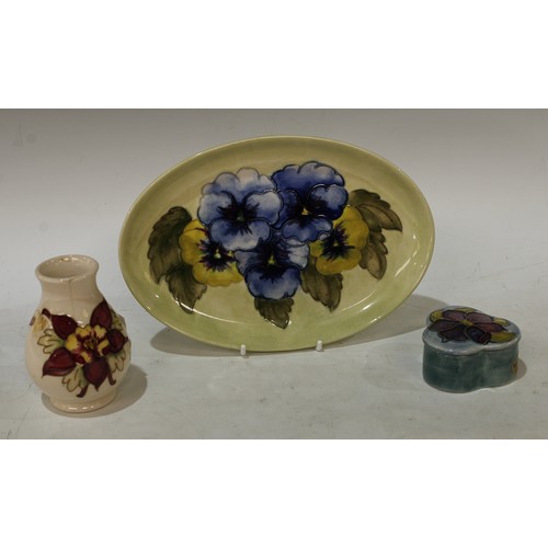 115 - A Moorcroft Pansy pattern oval tray, 23cm wide; an Anemone pattern trinket pot and cover; a small ba... 