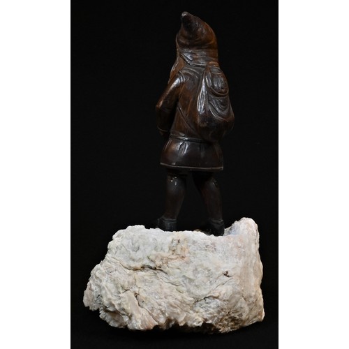 5078 - A Black Forest figure, carved as a mountaineering gnome, he stands, atop a quartz boulder, 24.5cm hi... 