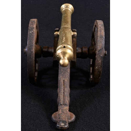 5083 - A brass and cast iron desk model cannon, 13cm barrel, spoked wheels, 20.5cm long overall