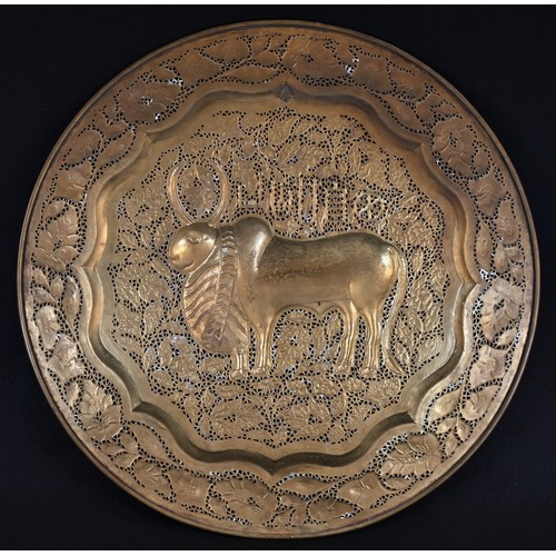 5182 - A Middle Eastern brass circular charger, chased with a stylised ox and devices, the ground and borde... 