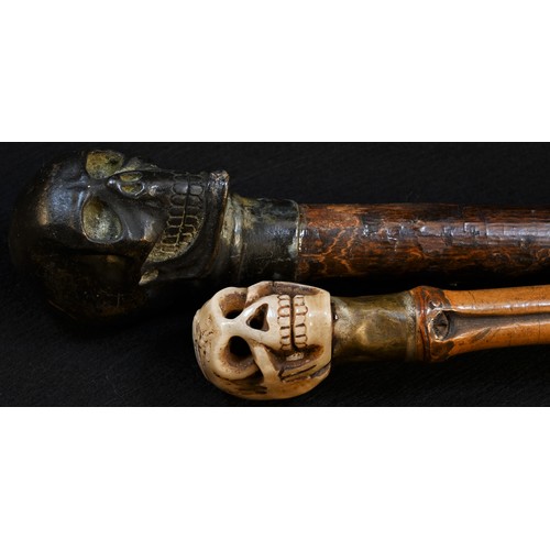 5090 - A bronze mounted momento mori walking stick, the pommel cast as a skull, 90cm long; another, similar... 