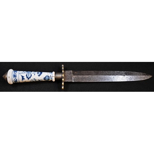 5603 - A 19th century dagger, 18.5cm pointed double-edged blade, shaped brass crossguard, the Meissen porce... 