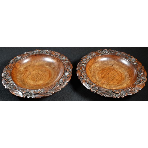 1509 - A pair of 19th century walnut shaped circular wine coasters, each carved with a border of flowers an... 