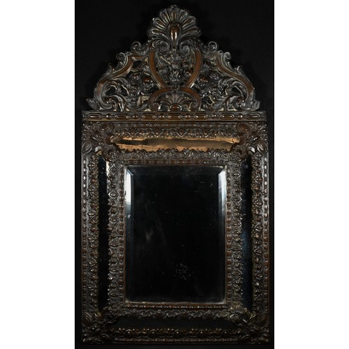 1500 - A Napoleon III shaped brown-patinated looking glass, bevelled mirror plate within a cushion frame, B... 