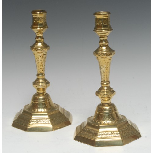 1520 - A pair of early 18th century French brass octagonal candlesticks, chased with flowerheads, stiff lea... 