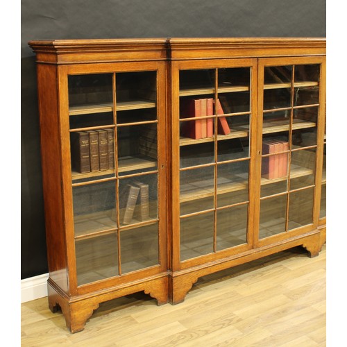 1825 - An early 20th century oak break-centre low library bookcase, moulded top above two pairs of glazed r... 