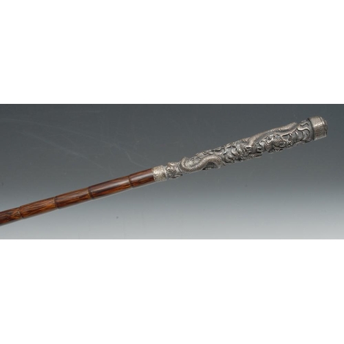 3580 - A 19th century Chinese walking cane, the tall silvered metal haft cast in relief with ferocious drag... 