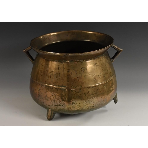 1450 - A 17th/18th century bronze tripod cauldron, flared rim and angular handles above a centre girdle, 36... 