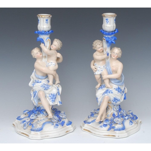 388 - A pair of German figural candlesticks, each with scantily draped maiden with child, picked out in to... 