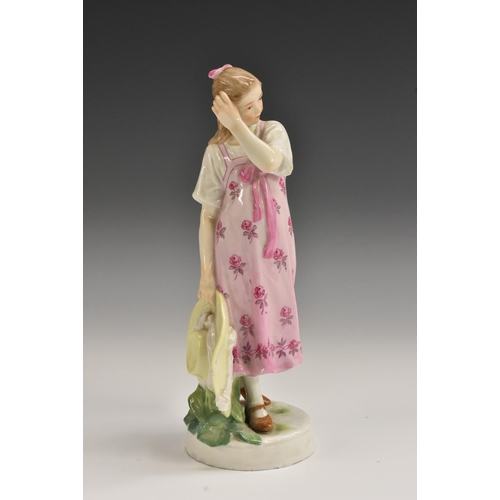 402 - A Meissen figure, of a young girl, she stands, wearing a long pink dress painted with flowers, her b... 