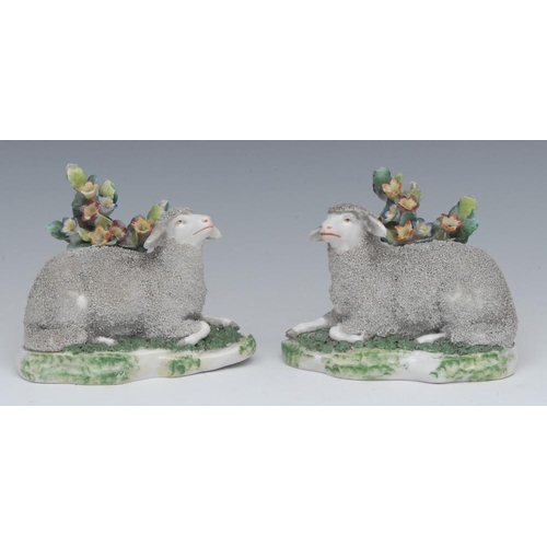 409 - A pair of French models, of sheep, reclining before bocage, shaped bases, 9cm high, c.1880