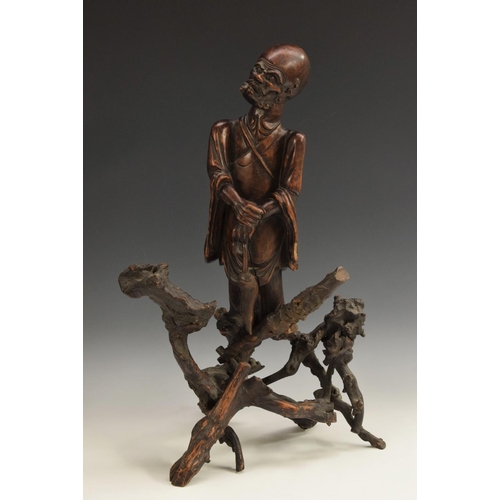 441 - A Chinese rootwood figure, carved as an immortal holding a fly whisk, 53cm high, 19th century