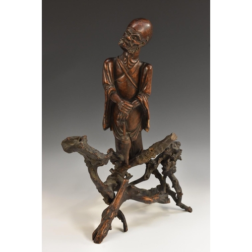 441 - A Chinese rootwood figure, carved as an immortal holding a fly whisk, 53cm high, 19th century