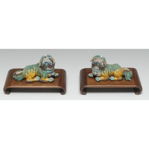 463 - A pair of Chinese spinach and egg glazed porcelain models, of temple lions, recumbent to left and ri... 